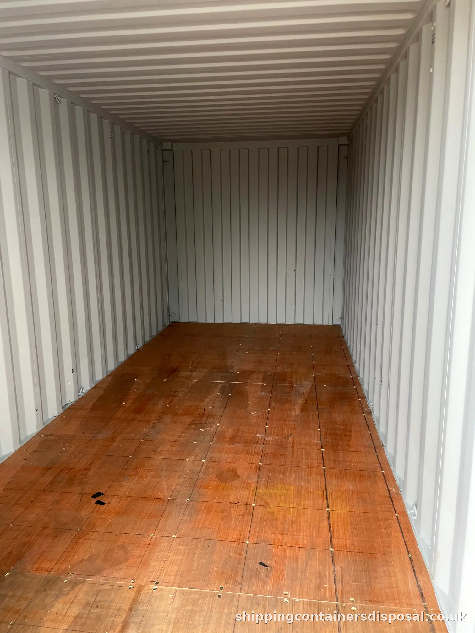 Clean shipping container interior with pale walls and timber floor Clean shipping container interior with pale walls and timber floor
