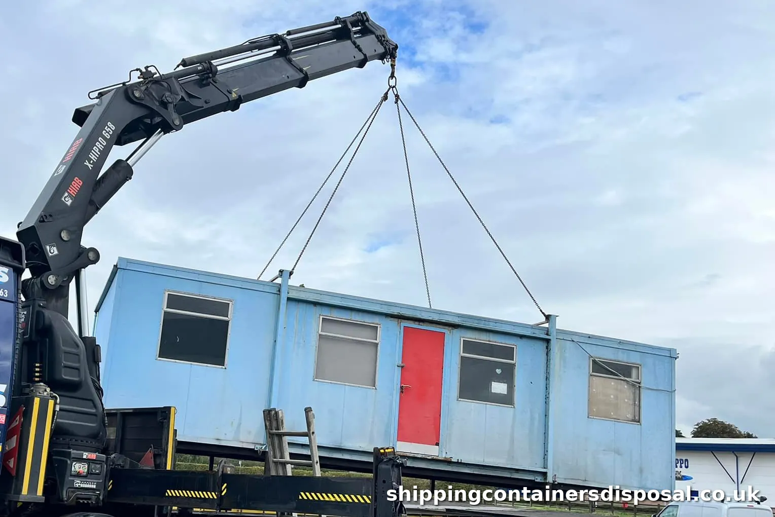 HIAB boom lifting a blue portable cabin with a red door HIAB boom lifting a blue portable cabin with a red door