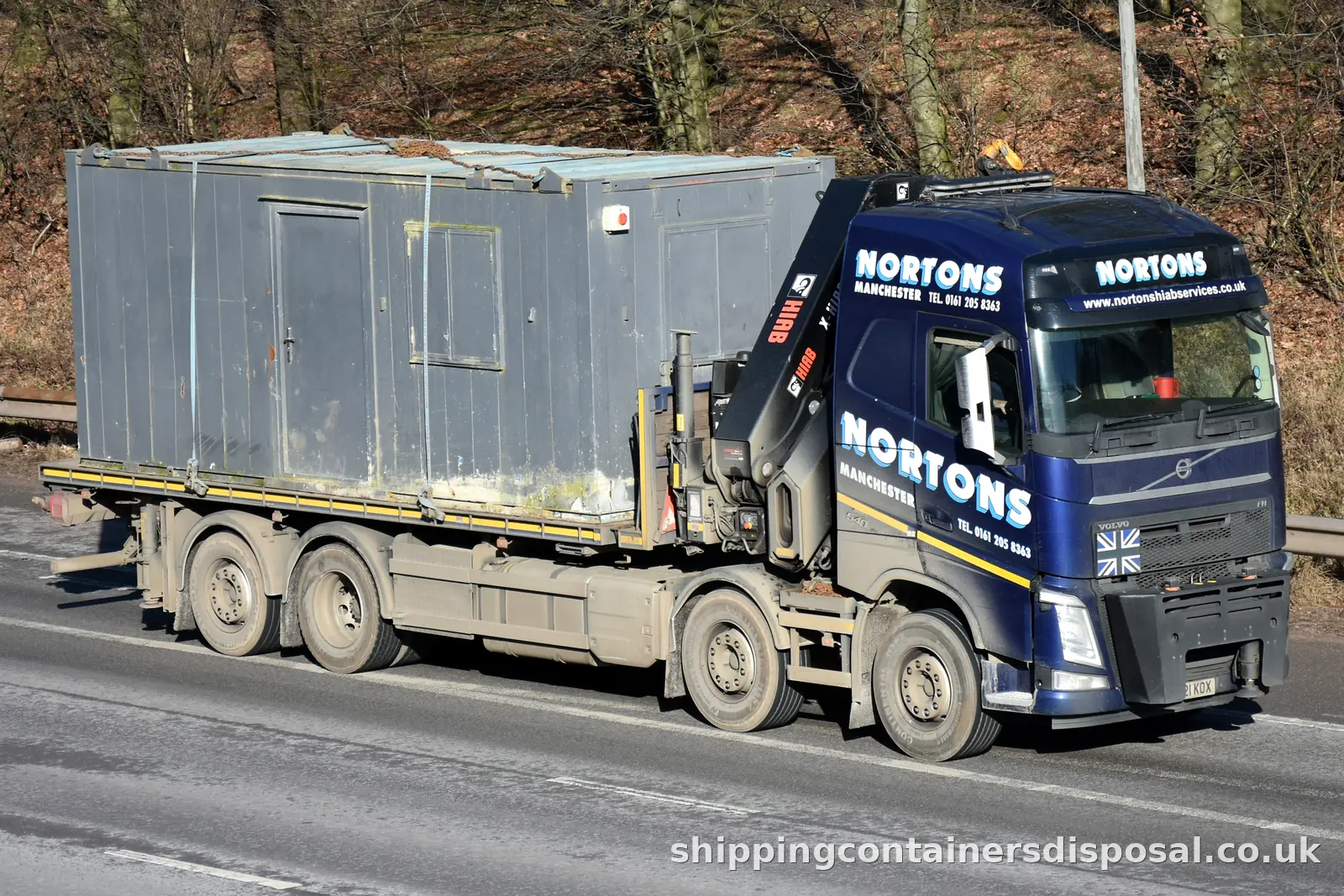 HIAB lorry carrying a grey site cabin on a dual carriageway