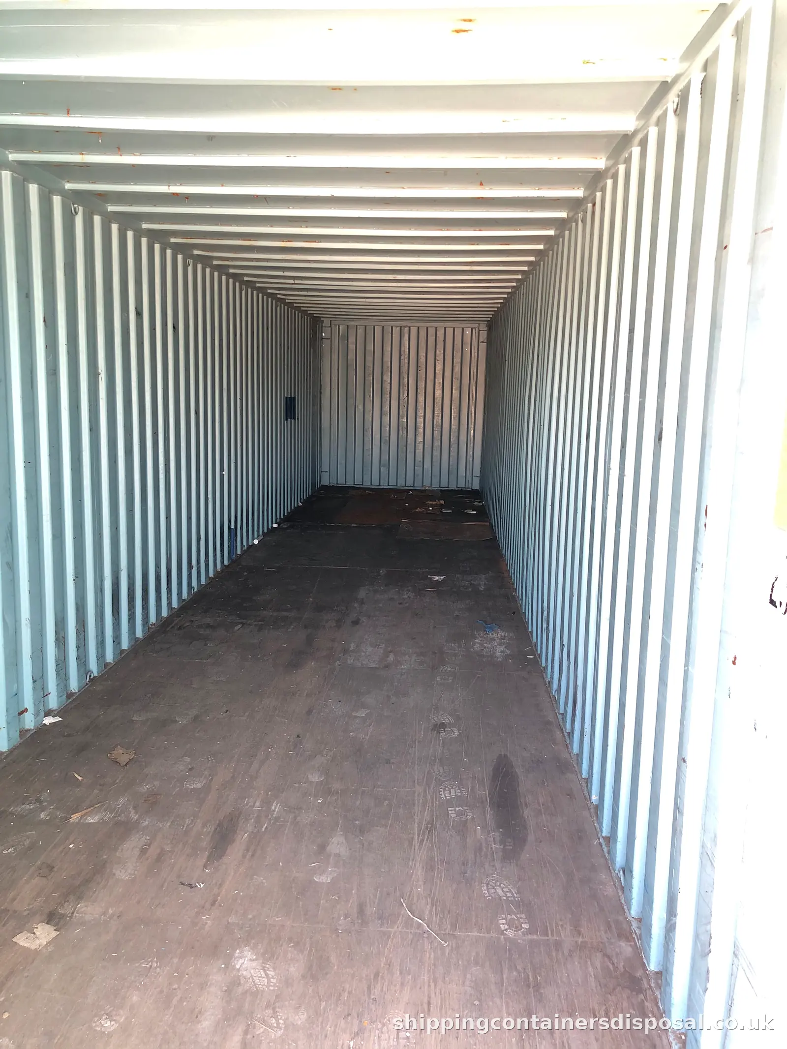 Long empty shipping container interior with a worn floor