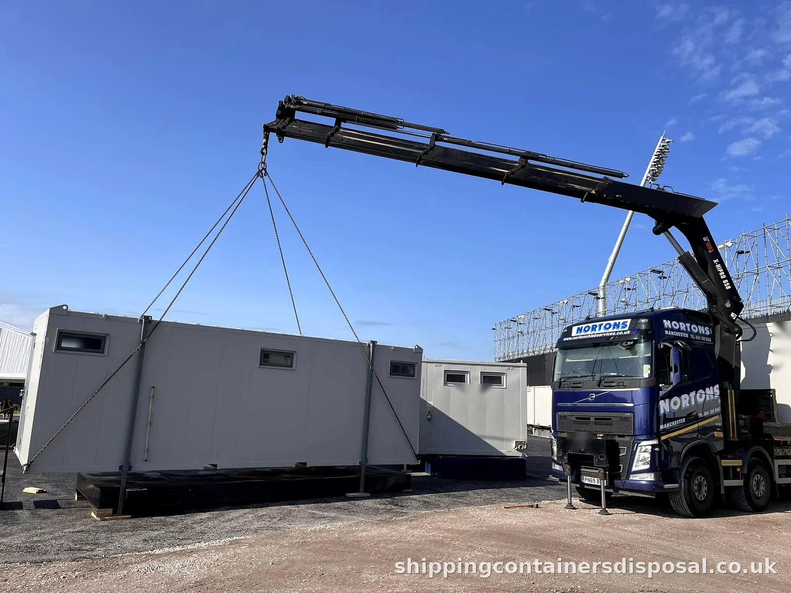 Grey portable cabin lifted on chains by a HIAB lorry Grey portable cabin lifted on chains by a HIAB lorry