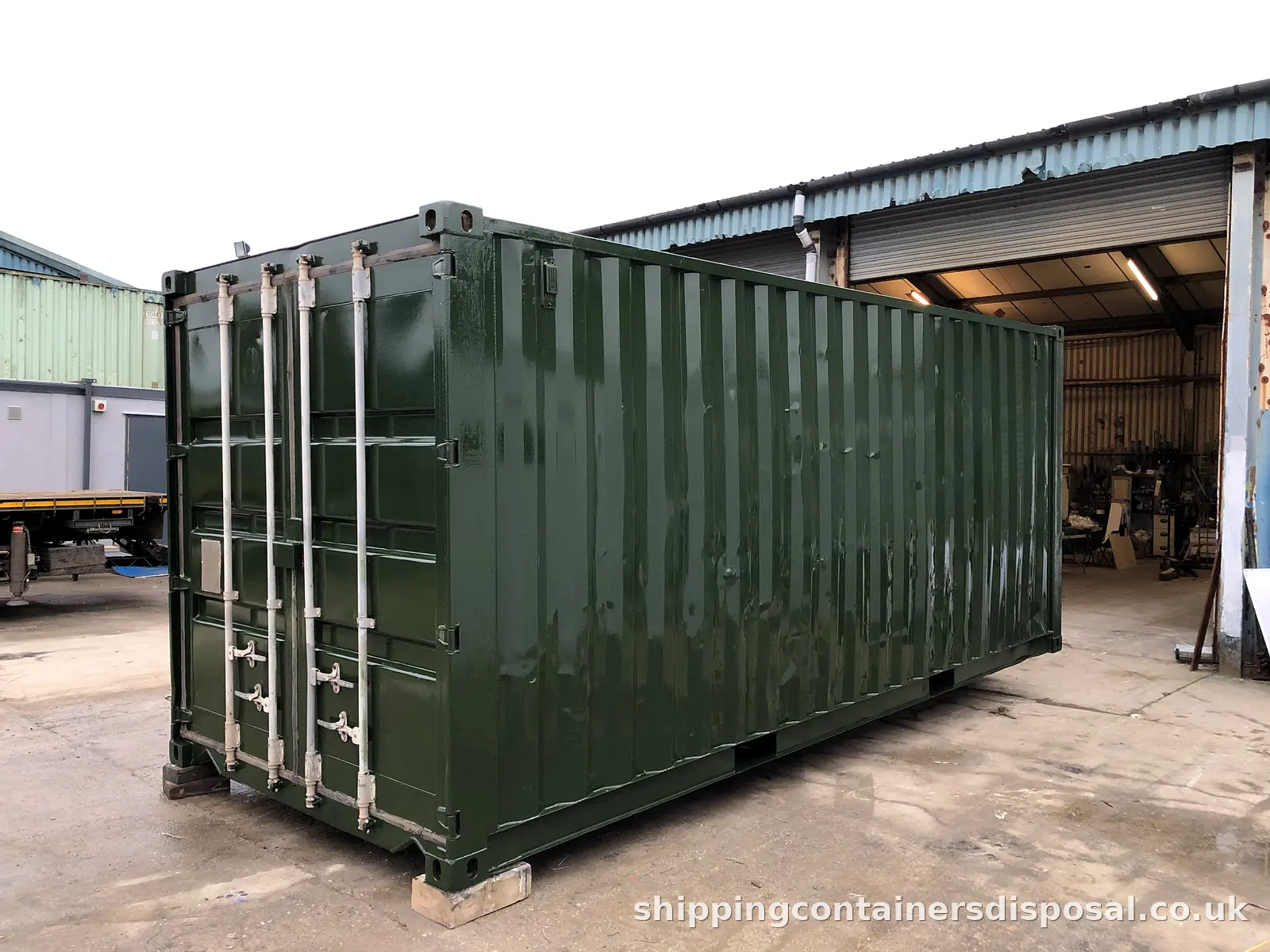 Repainted dark green 20ft shipping container outside a workshop Repainted dark green 20ft shipping container outside a workshop