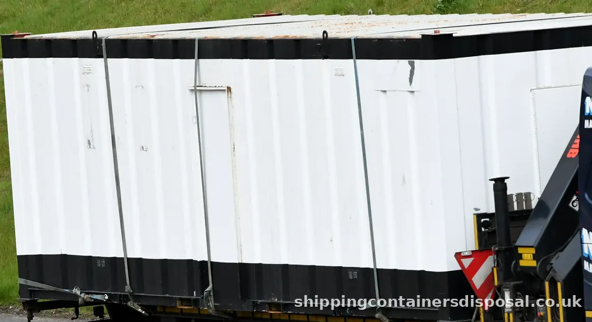 Side of a white steel site unit strapped to a lorry Side of a white steel site unit strapped to a lorry